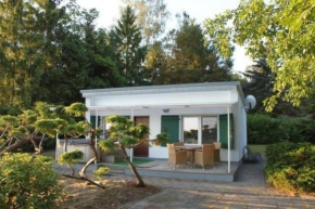 Freistehendes kleines Ferienhausaus mit Whirlpool im Außenbereich und einem Paddelboot umgeben von Wäldern und Wiesen